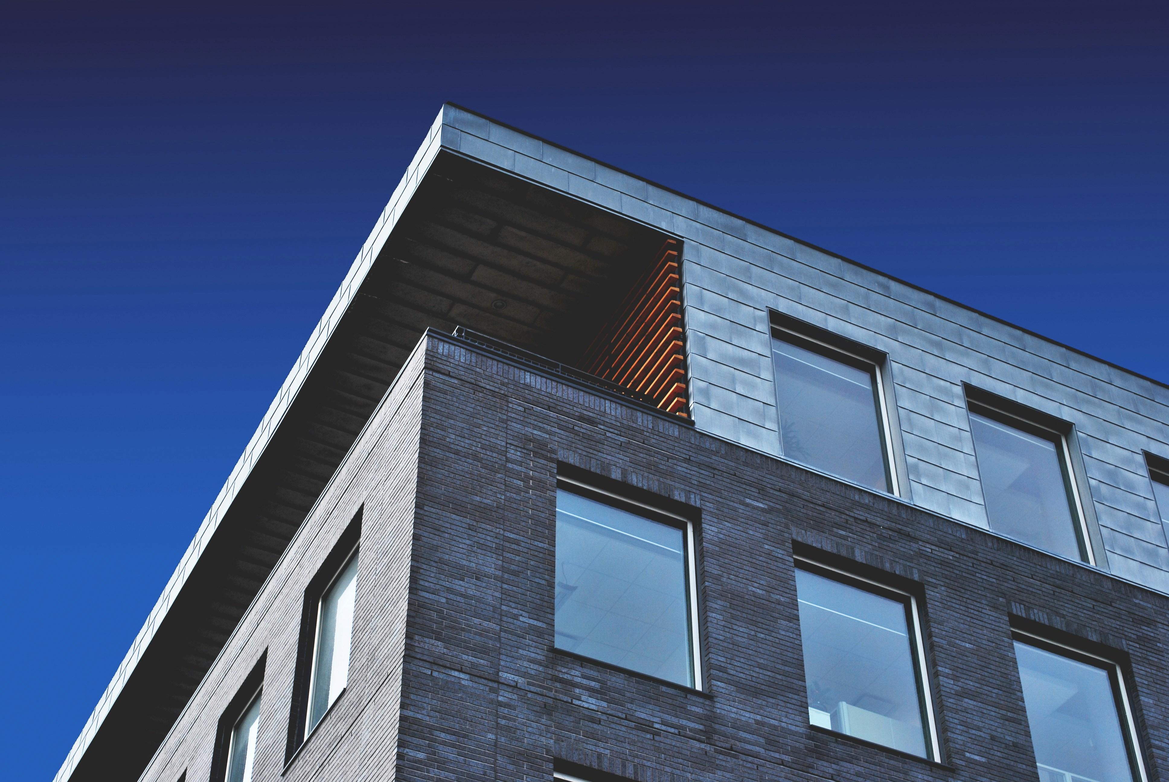 The corner of a brick and metal building against a deep blue sky