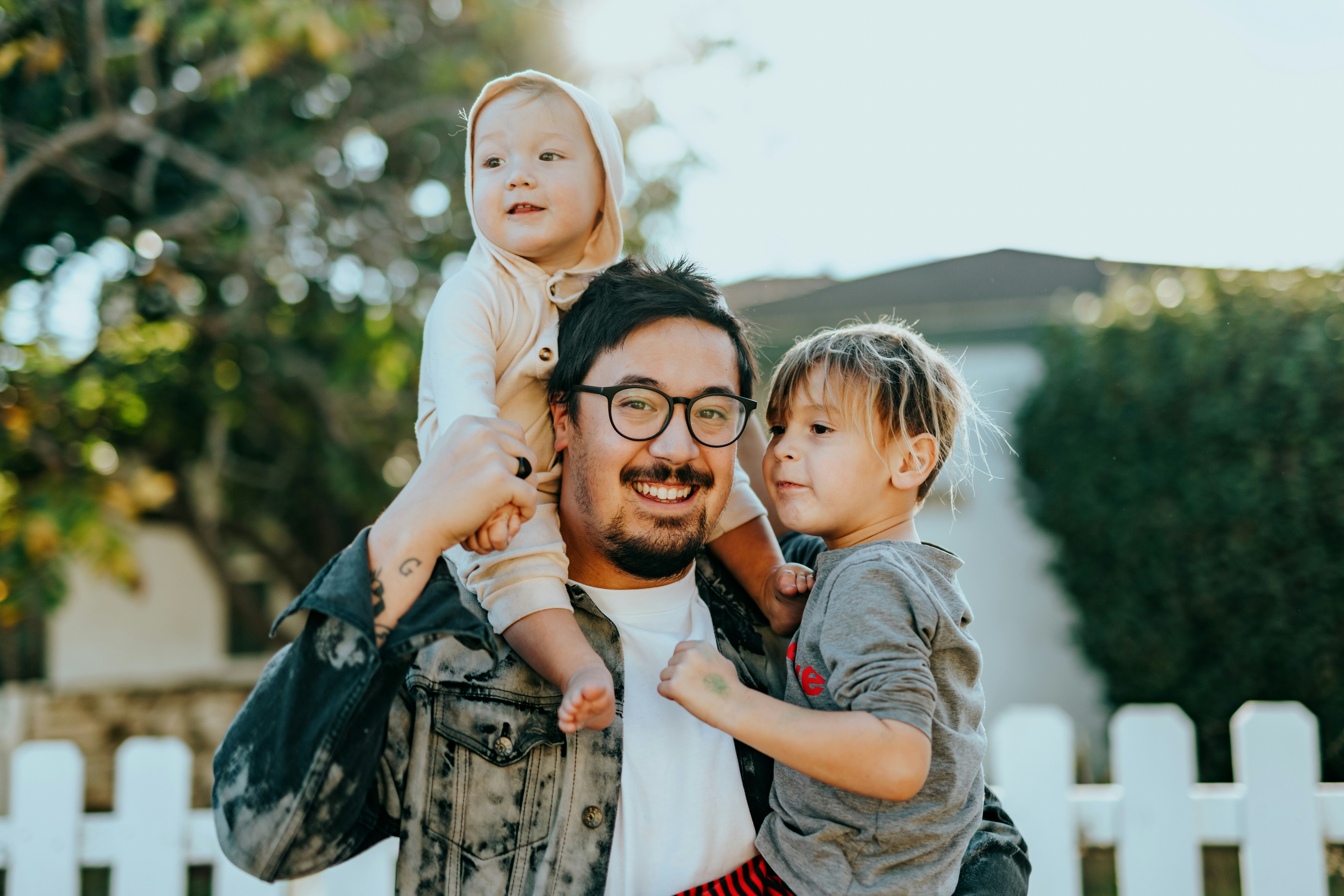 A father carrying his two young children outside their home