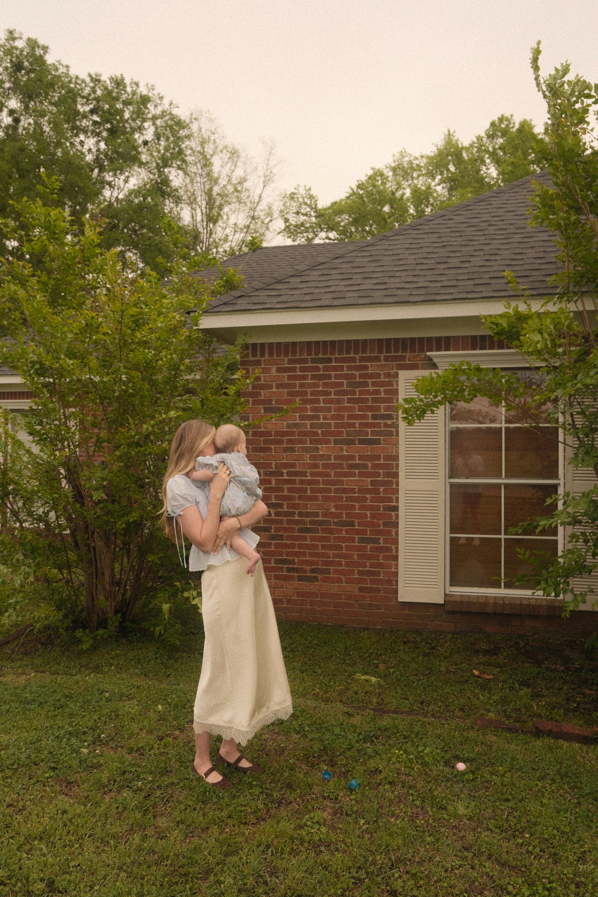 A mother holding her baby in the garden of their home