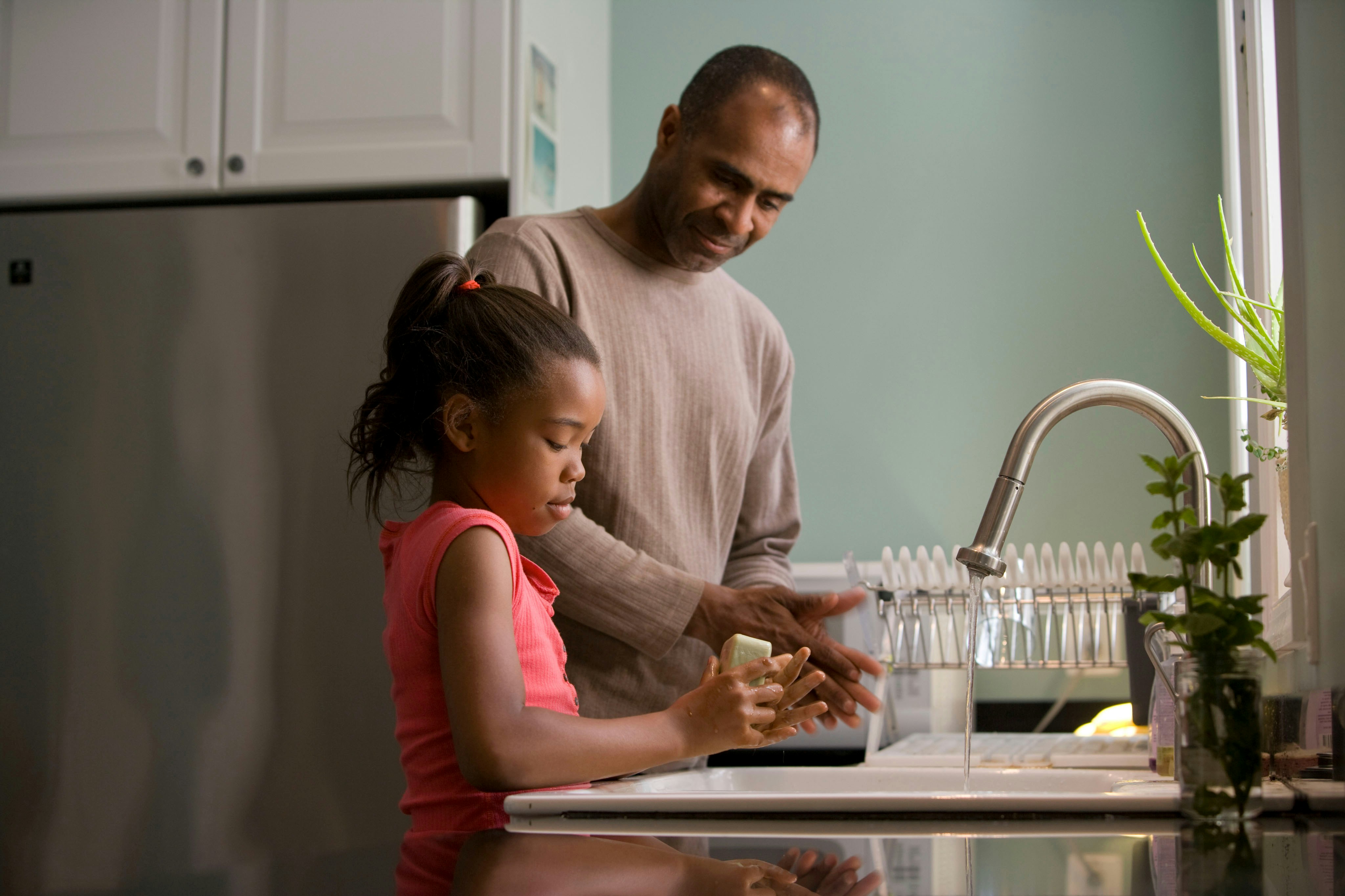 A father and his daughter washing up at the kitchen sink